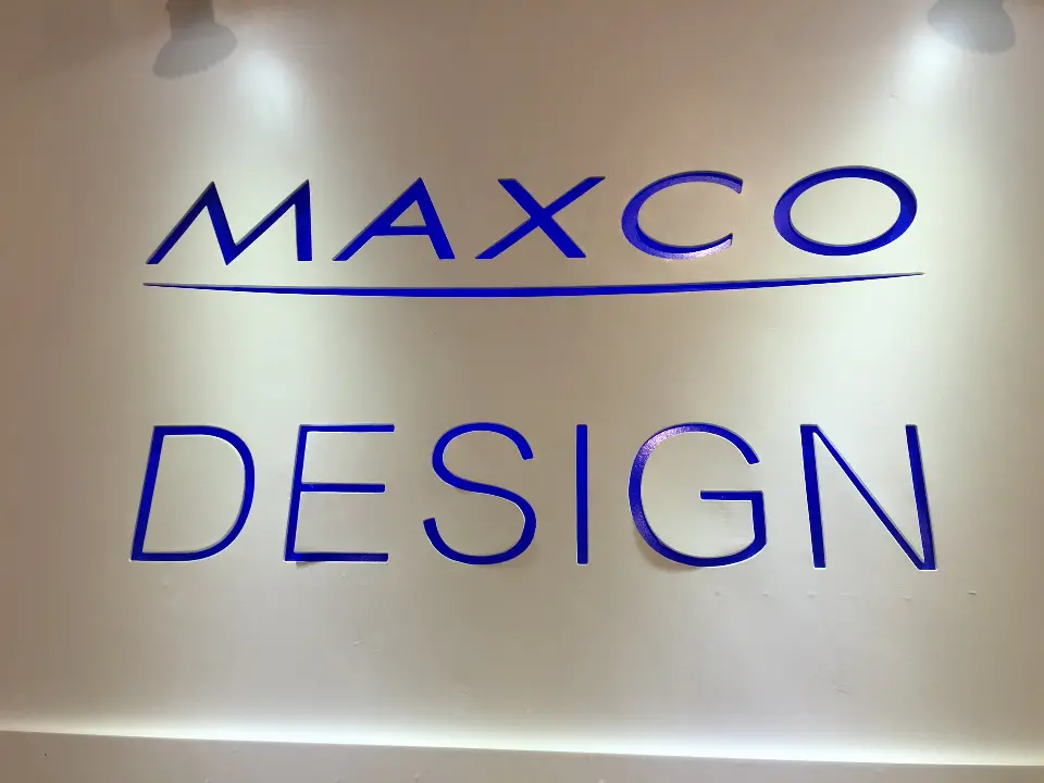 Blue MAXCO DESIGN lettering centered on a white wall panel