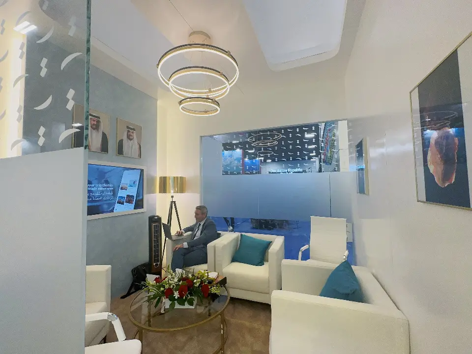 Meeting room with ring pendant light, white sofas and teal cushions