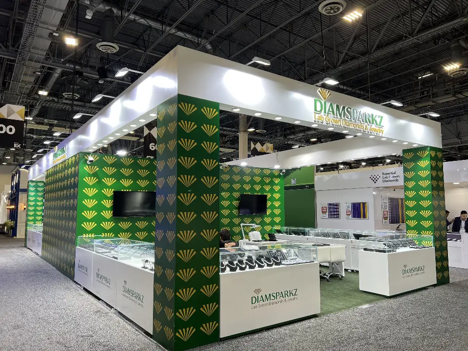 Corner view of Diamsparkz booth with green gold-patterned pillars, white header and white showcases