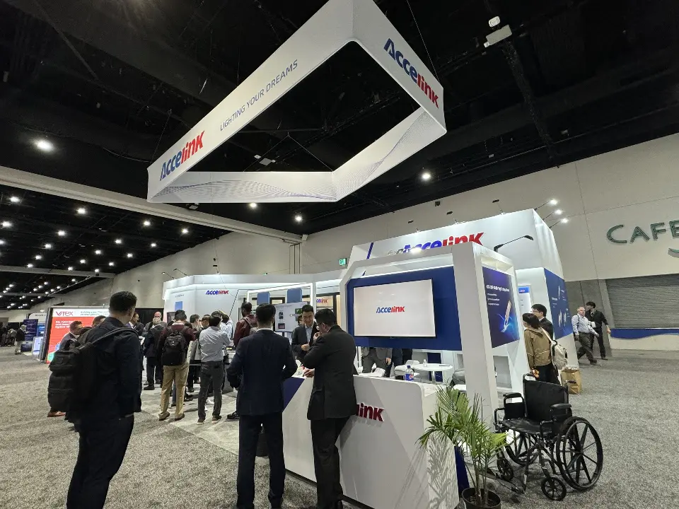 Visitors at the Accelink booth under the triangular hanging sign with red logo