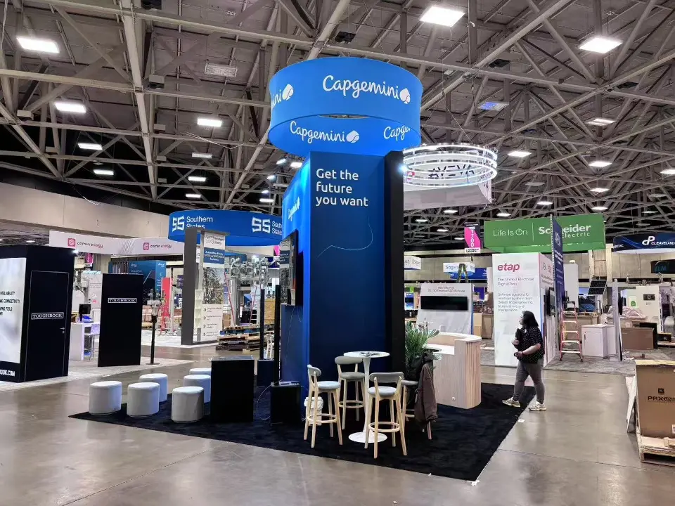 Corner view of the stand with high tables and round stools on dark flooring
