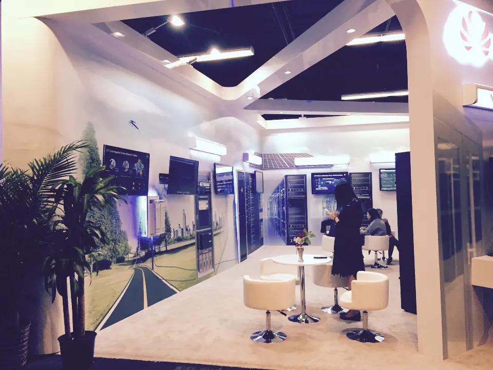 Inside the booth with a palm plant, white stools and the landscape mural