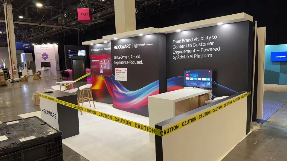 Hexaware booth corner with Adobe AI Platform message, wall screens and caution tape still up