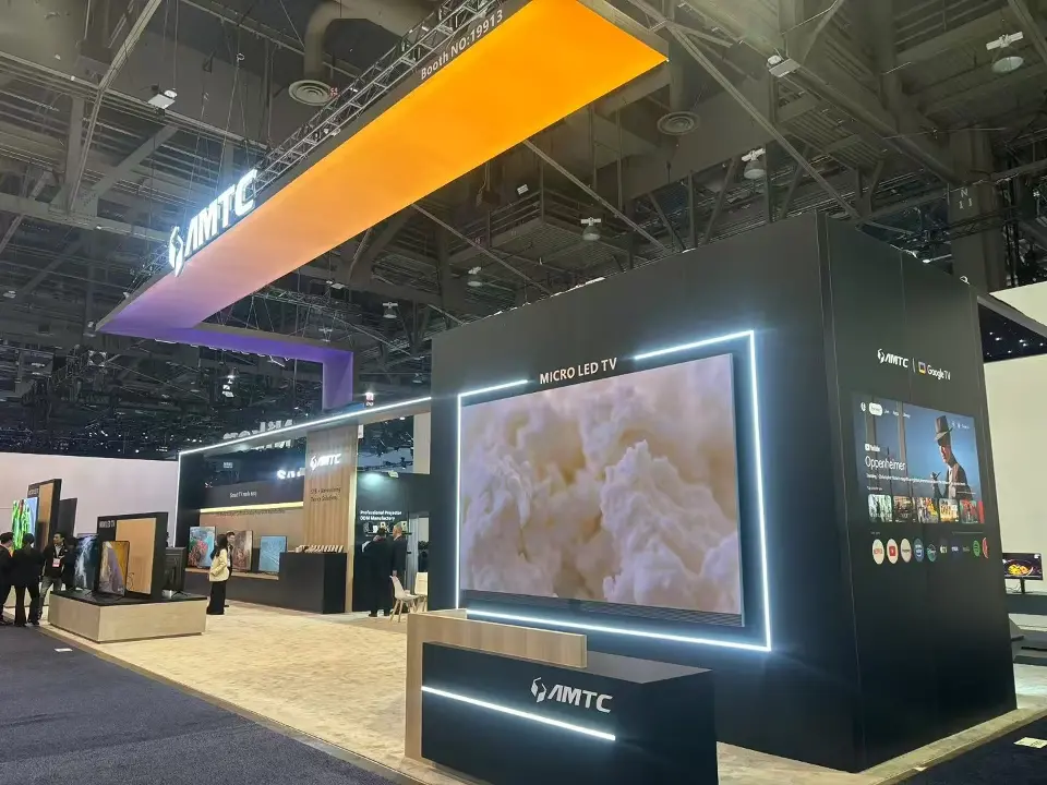 AMTC black display block framing a large Micro LED TV with a lit AMTC counter in front