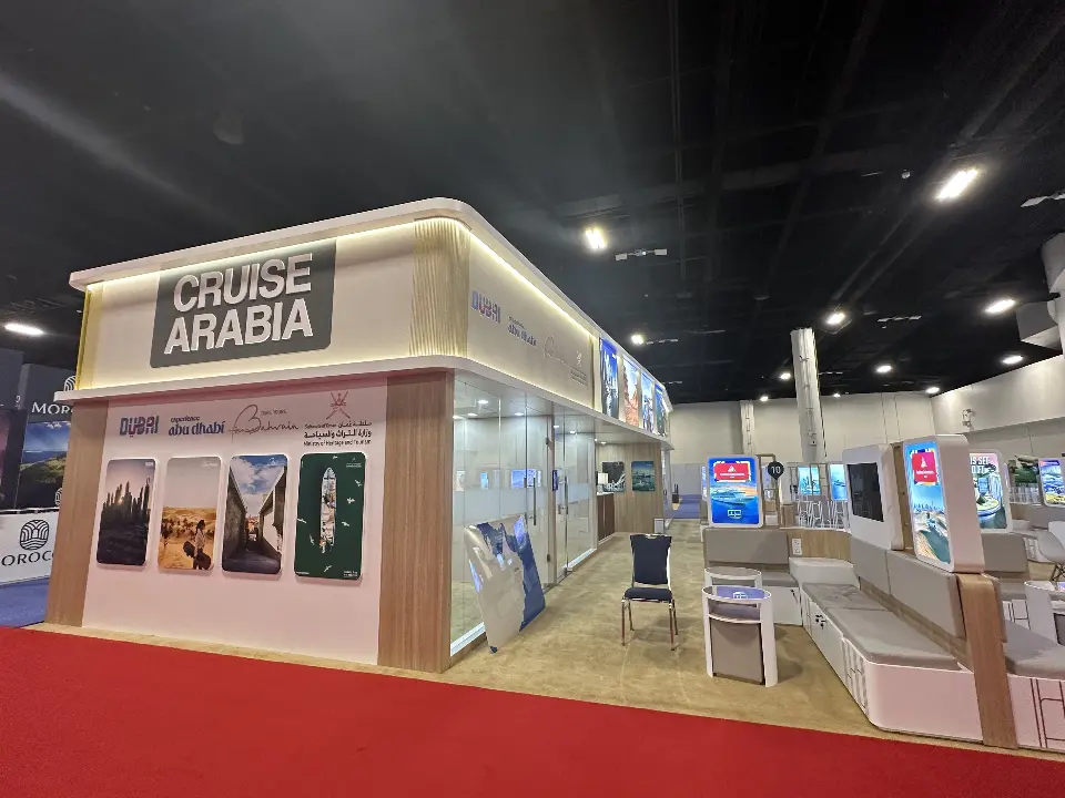 Corner of the Cruise Arabia pavilion with backlit Cruise Arabia header, destination photo panels and glass meeting rooms
