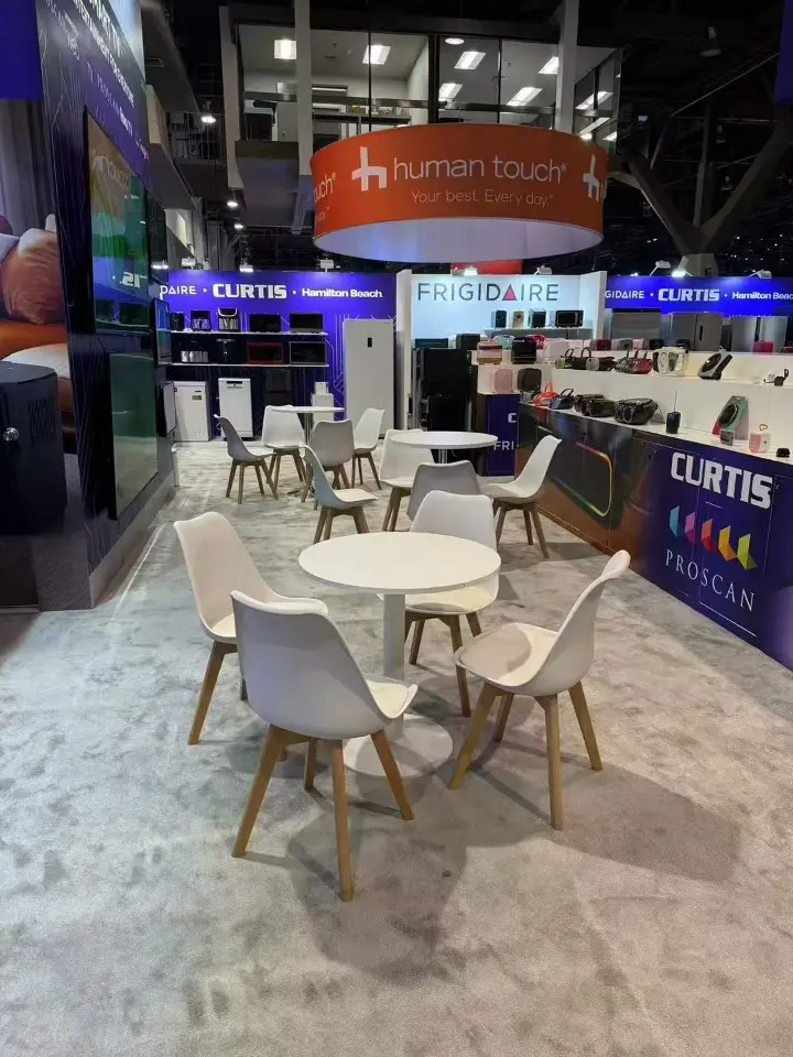 Meeting area inside the Curtis stand with round white tables and chairs beside branded walls