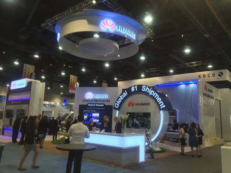 Crowd in the aisle in front of the white booth, screens and arched band