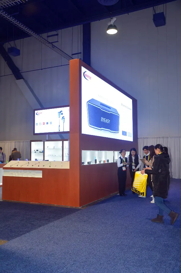 Booth corner with a lit graphic panel seen from the aisle