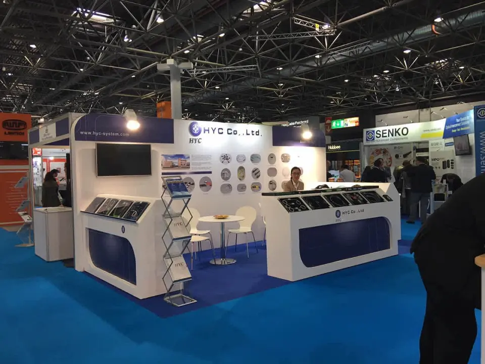 White booth with dark-blue curved counters, wall screen and wire brochure stand