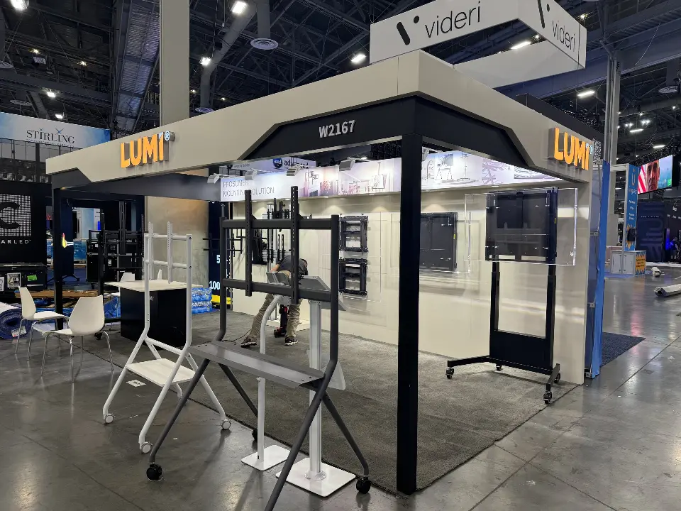 Front corner of the Lumi booth with yellow lit LUMI header and mobile TV stands