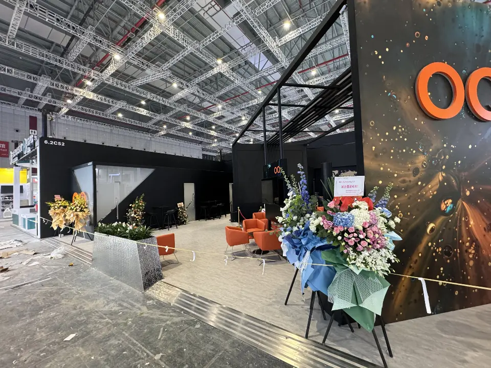 Close angle of the OQ graphic tower with flower arrangements beside the booth entrance