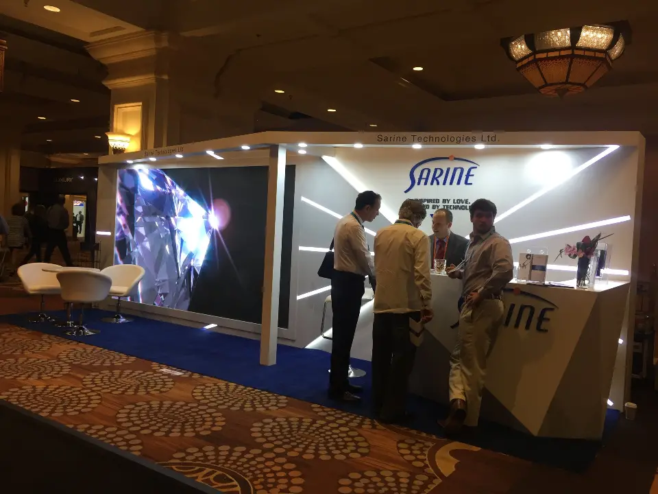 Wider view of the Sarine booth with staff and guests in front of light strips