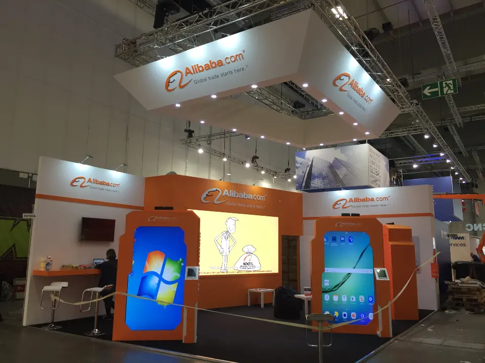Evening view of the booth with three lit screens in orange frames