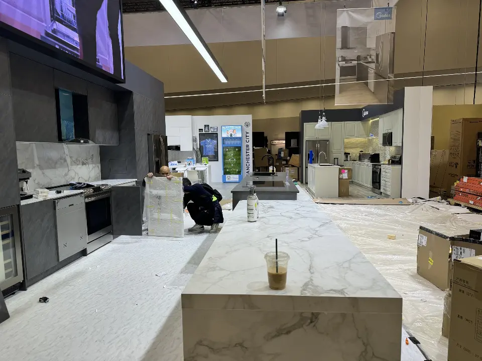 Marble-look island counter with a dark kitchen wall behind it
