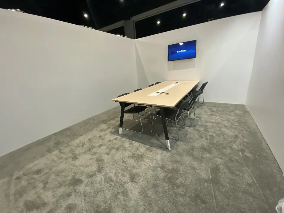 Meeting room with long table and wall screen on grey carpet