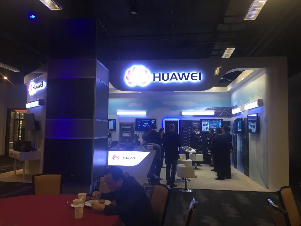 Huawei booth front with the lit logo over a doorway and the blue-lit column