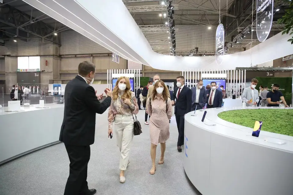 Visitors in masks walking past the round counter with grass top