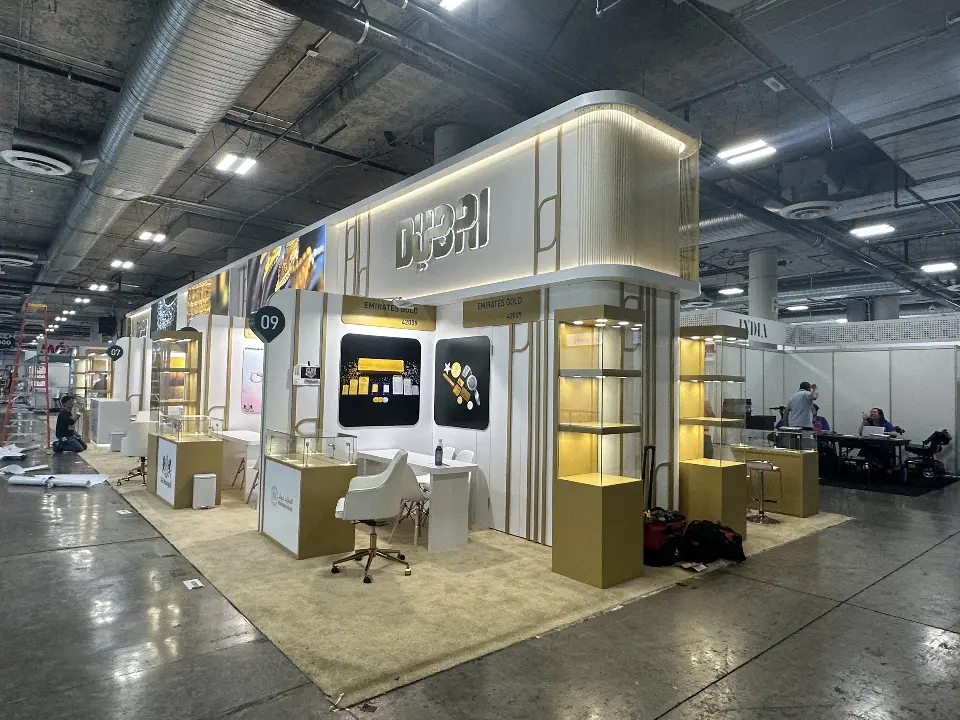 Pavilion front with visitors passing a tall lit gold showcase