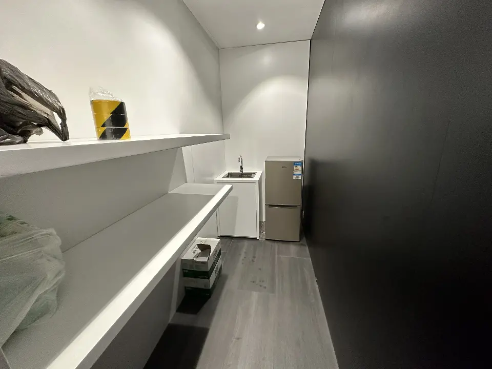 Storage room with white shelves, counter space and a small fridge