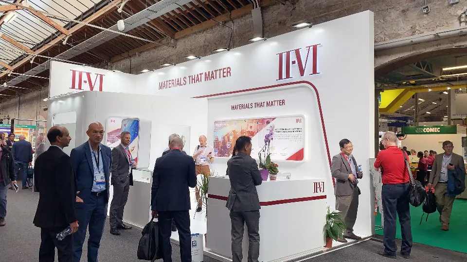 Busy aisle view with groups talking in front of the backlit graphic wall