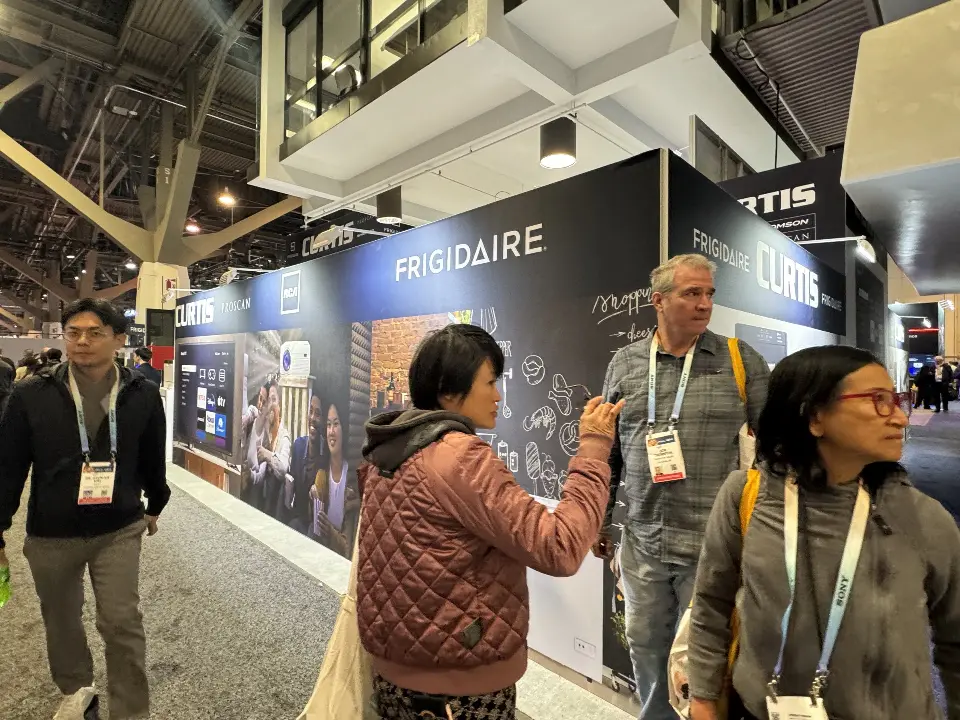 Visitors walking past the Frigidaire wall at the booth edge