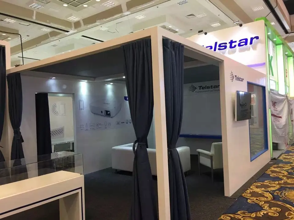 Inside a curtained Telstar meeting room with white seating and a wall screen