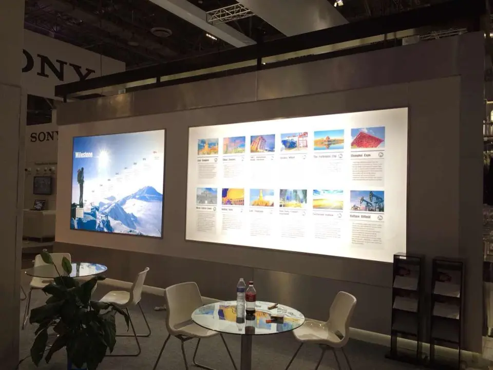 Backlit photo wall with framed images beside a lounge of white chairs and round table