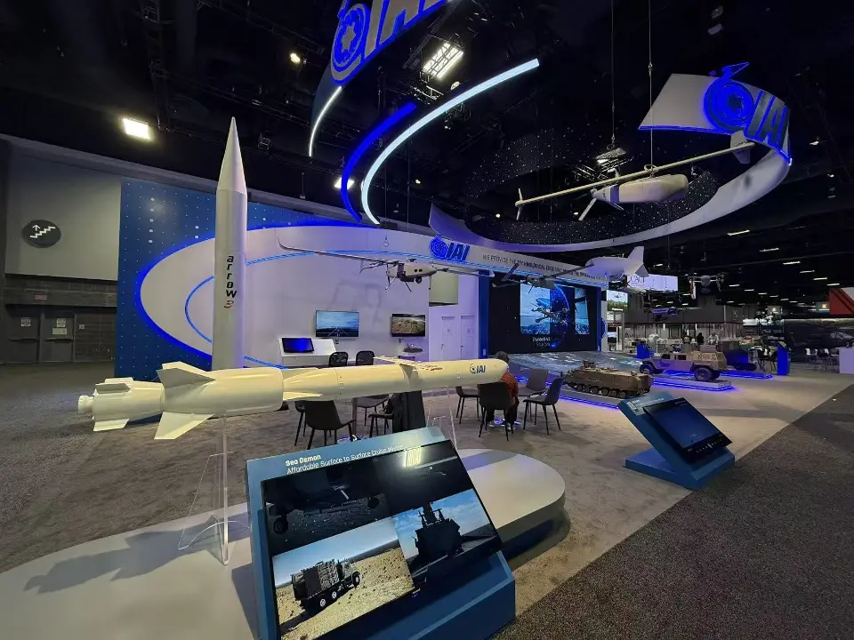 Close angle of a white missile model and tilted display screens on lit plinths