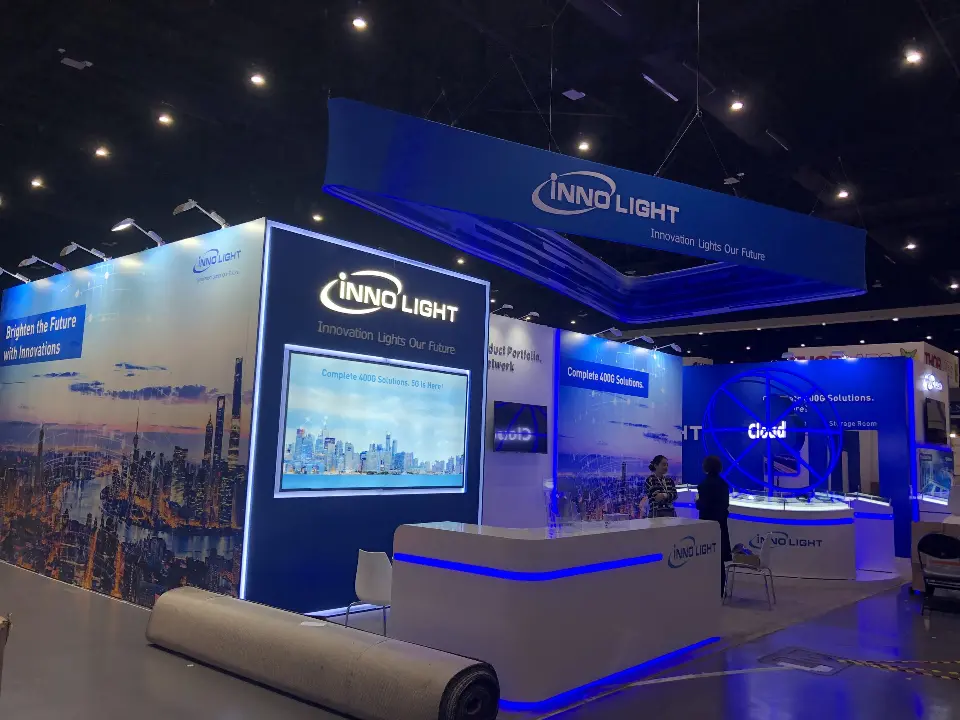Front of the InnoLight booth with skyline graphic, screen and hanging square sign