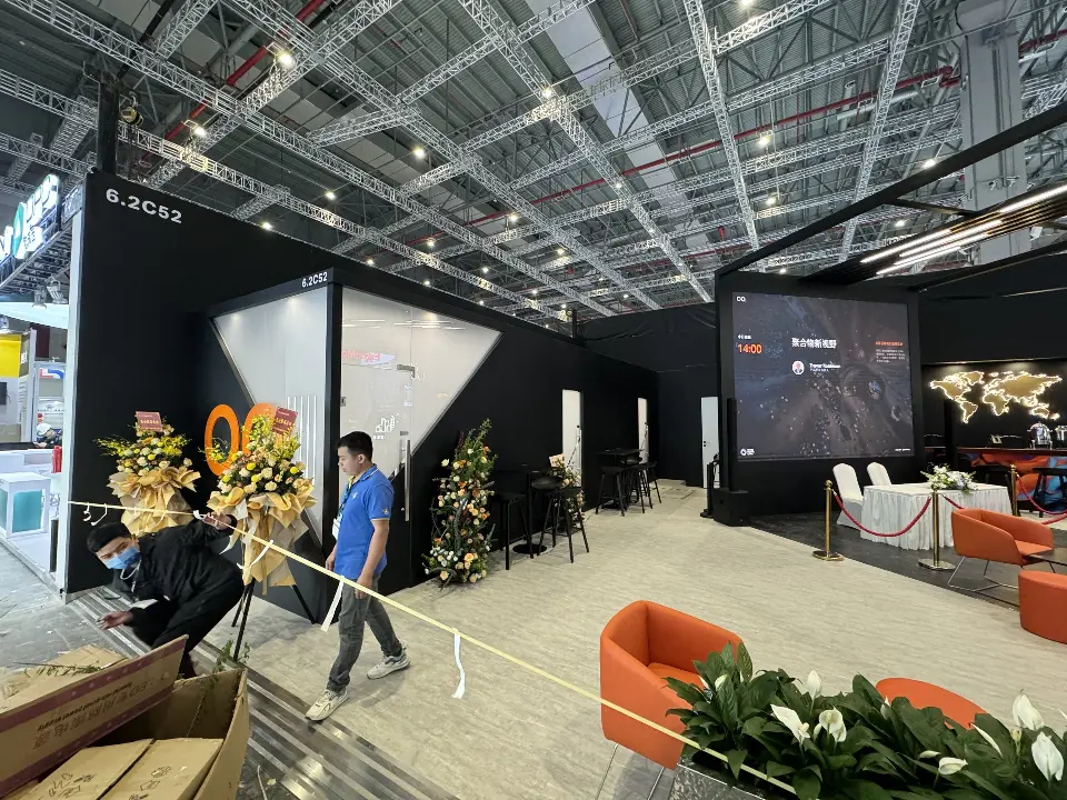 Side entrance view with white lounge chairs, flowers and a large video screen