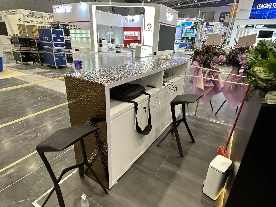 Bar counter with textured bronze-tone end panel and black stools