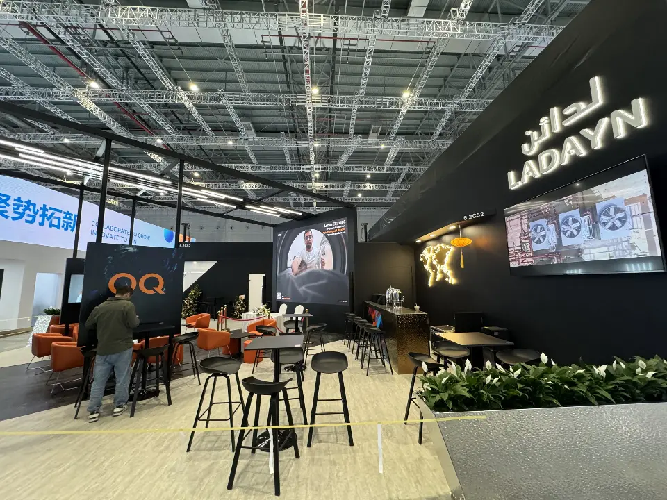 Lounge corner with lit LADAYN lettering, video screen, bar counter and black high tables