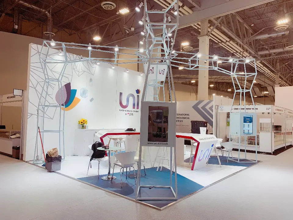 Front view of uni booth with wire-frame canopy, logo wall and blue floor inset