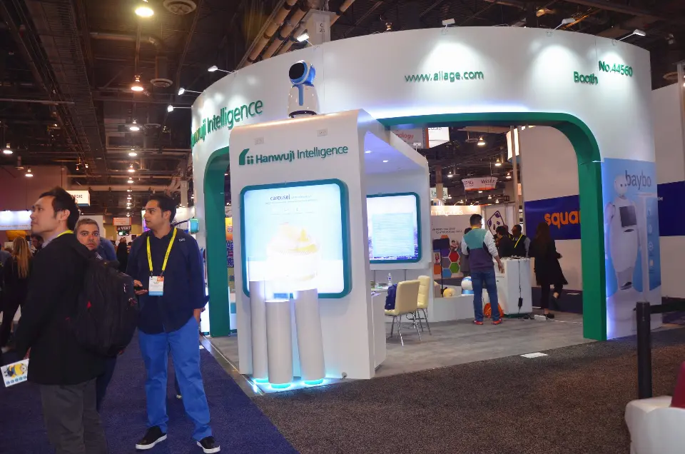 Front portal with backlit robot screen as visitors walk past the booth
