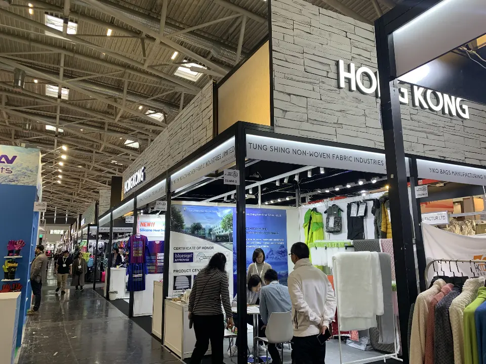 Aisle view of open stands with apparel and product graphics under the pavilion header