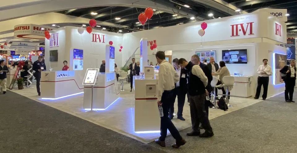 Aisle view of visitors at kiosks with red and white balloons above