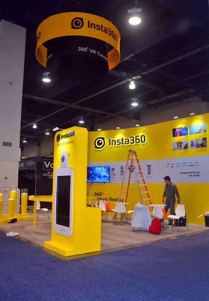 Round yellow Insta360 hanging sign above the booth, seen from below