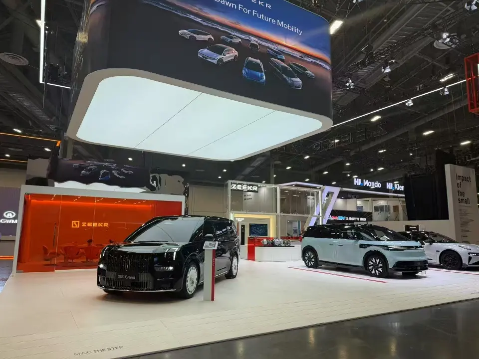 Vehicles on the white floor beneath a backlit ceiling panel and red wall