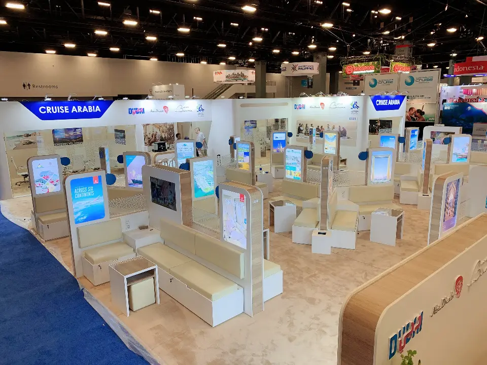 Wide view of the white island booth with backlit lounge pods and a corner counter