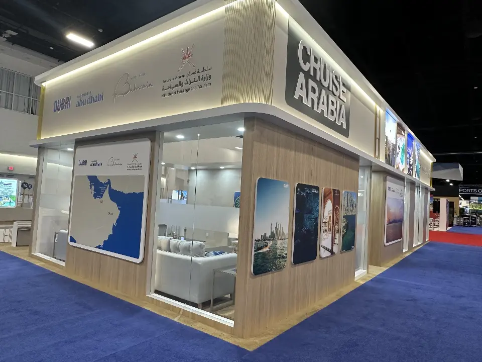 Corner of the Cruise Arabia booth with lit wood-look header and map graphic
