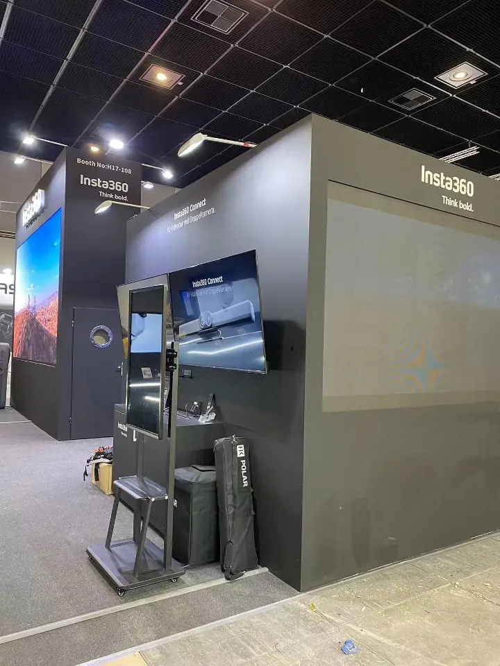 Side wall with a mounted screen and product display stands beside a black tower