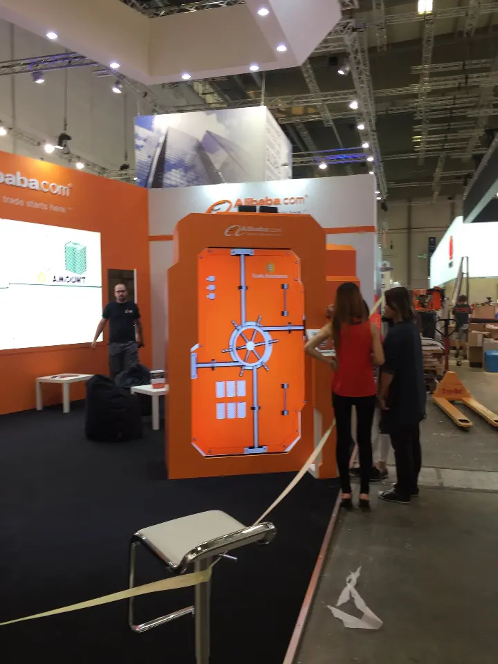 Portrait view of an orange vault-style door and visitors inside the booth