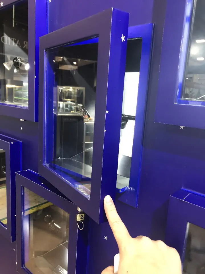 Hand pointing at an open niche door on the blue wall