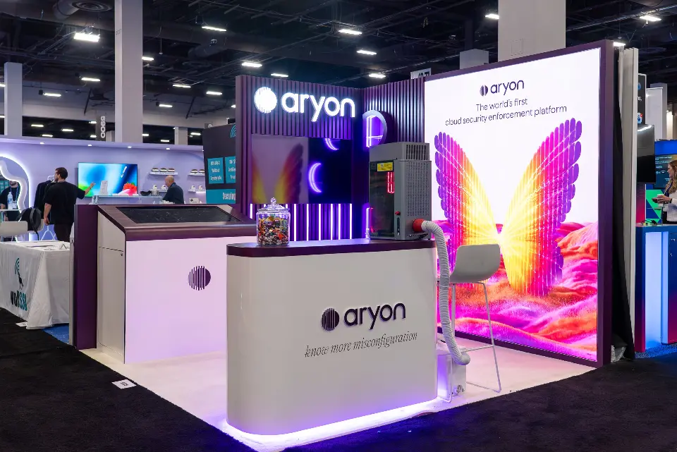 Side angle of the Aryon booth with the touchscreen kiosk and purple-lit counter base