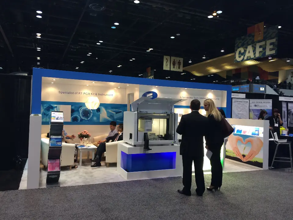 Side view of the URIT booth with lit inner display and visitors at the edge
