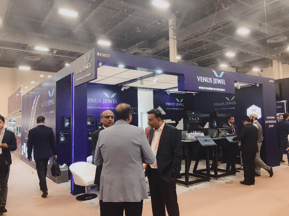 Visitors gathered by the booth corner beside framed jewelry niches