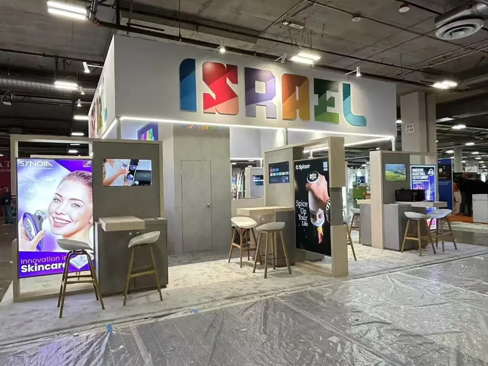 Side view of the Israel Pavilion with backlit skin care graphic and wood-look counters