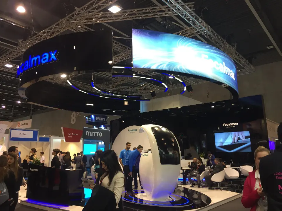 Busy show floor in front of the Focalmax stand with ring header and white pods
