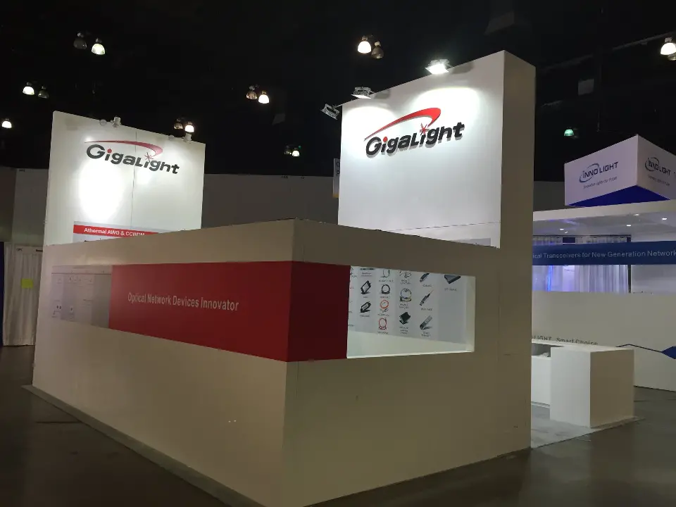 Closed side wall of the Gigalight booth with red band and backlit logo above