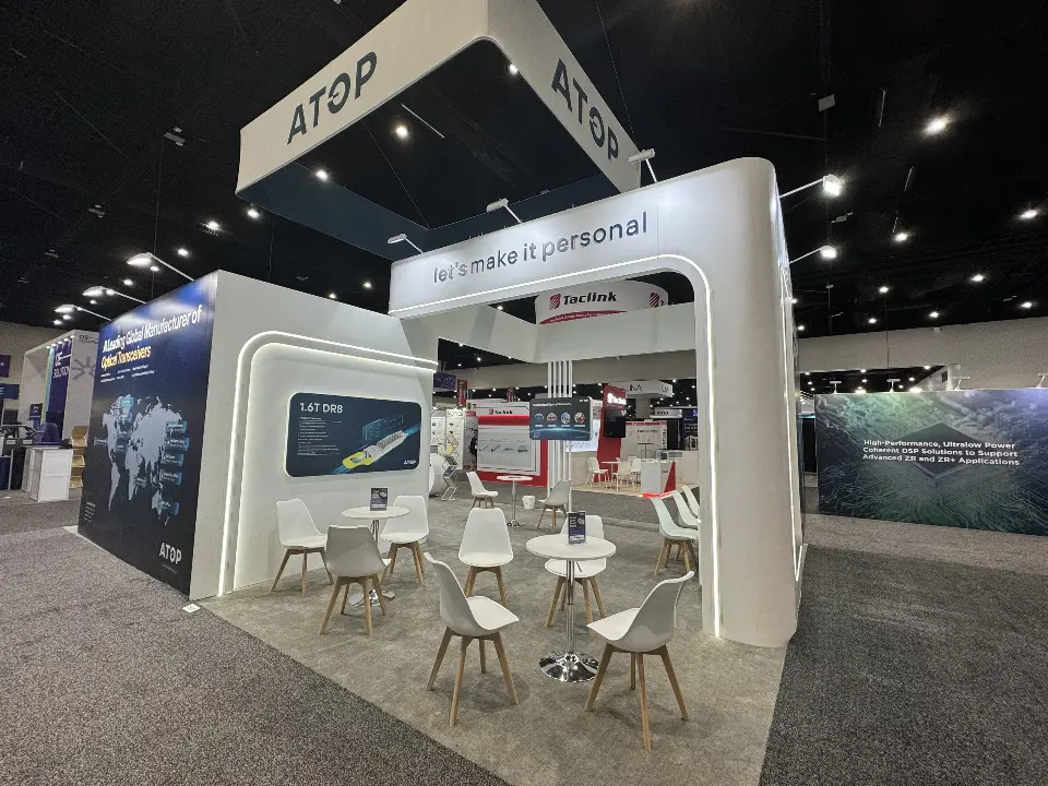 Rear meeting area with white tables and chairs beneath ATOP hanging headers